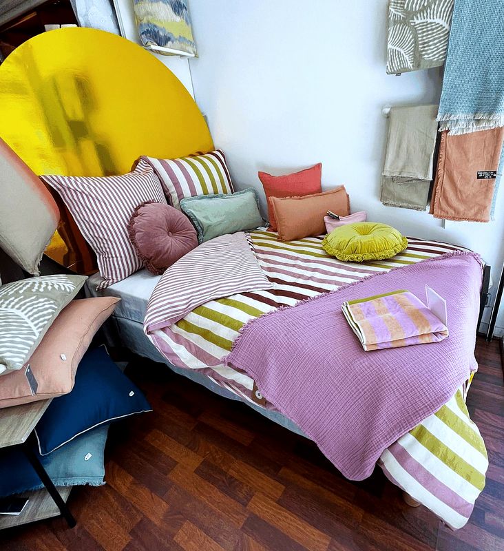 Un lit habillé de linge rose et de coussins dans la boutique